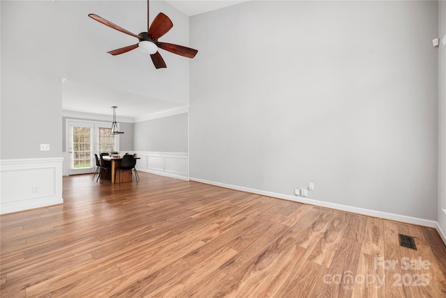 unfurnished living room with ceiling fan, light wood-type flooring, and ornamental molding