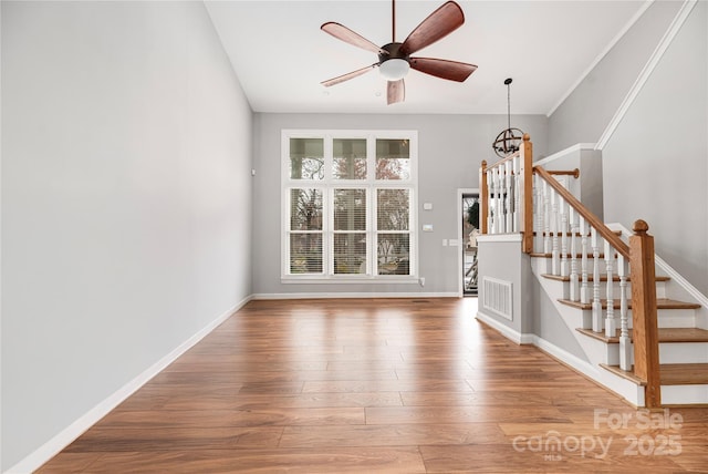 unfurnished living room featuring wood-type flooring and ceiling fan with notable chandelier