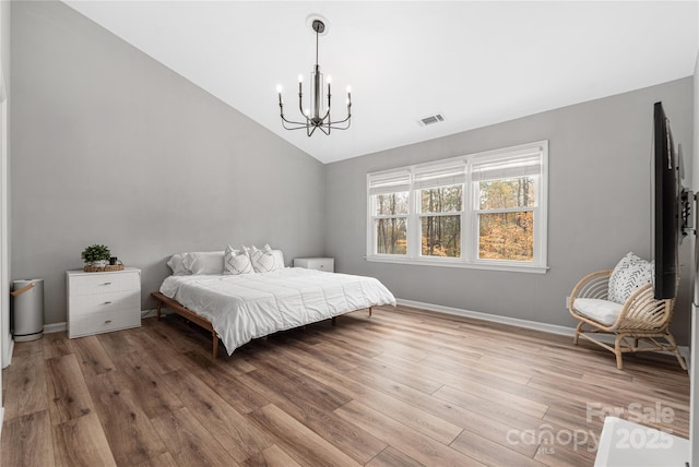 bedroom with hardwood / wood-style flooring, lofted ceiling, and a notable chandelier