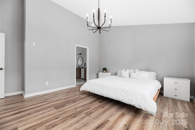 bedroom with ensuite bath, light hardwood / wood-style floors, vaulted ceiling, and an inviting chandelier