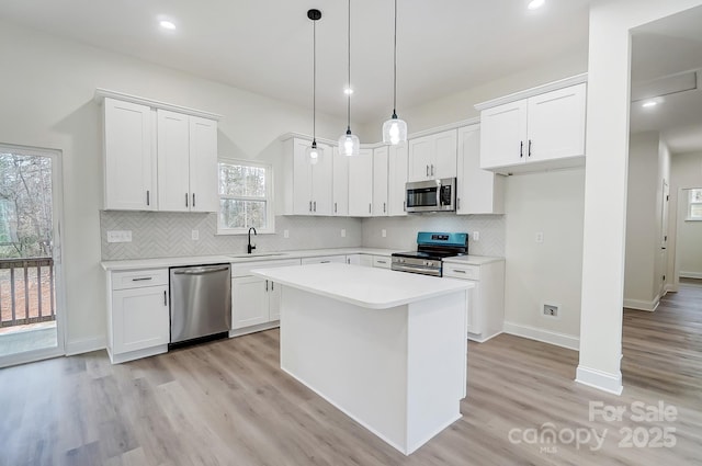 kitchen with stainless steel appliances, a sink, light countertops, and white cabinetry