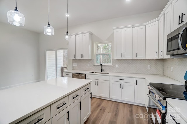 kitchen featuring white cabinetry, stainless steel appliances, a sink, and light countertops