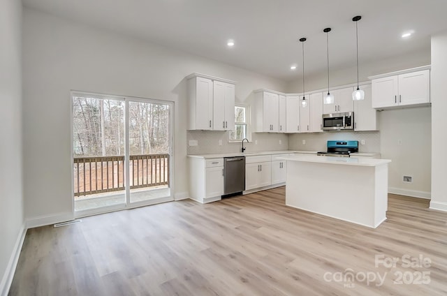 kitchen with stainless steel appliances, light countertops, white cabinetry, and tasteful backsplash