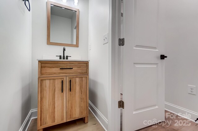 bathroom featuring vanity, baseboards, and wood finished floors