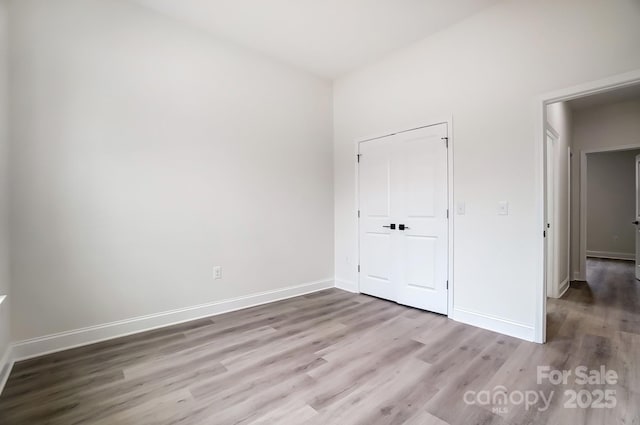 unfurnished bedroom featuring wood finished floors and baseboards