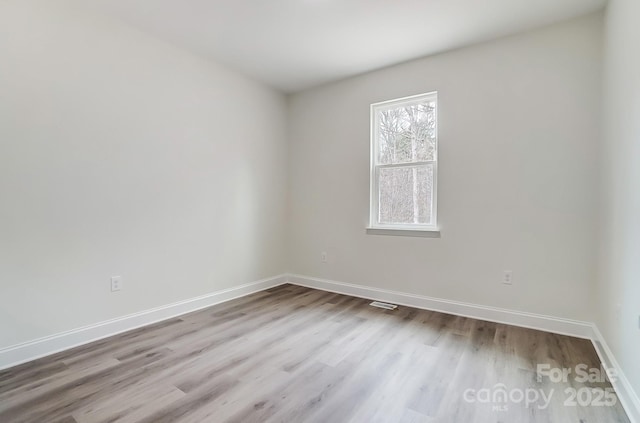 unfurnished room with wood finished floors, visible vents, and baseboards