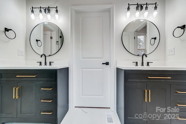 full bath featuring marble finish floor, visible vents, two vanities, and a sink