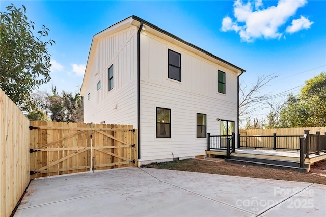 rear view of property featuring a wooden deck, fence, and a gate