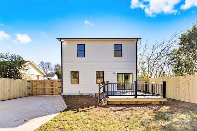 back of house with a deck, board and batten siding, a fenced backyard, and a gate