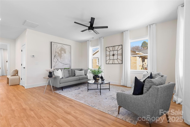 living room featuring visible vents, wood finished floors, baseboards, and ceiling fan