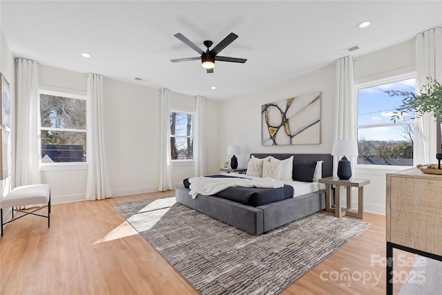 bedroom featuring multiple windows, wood finished floors, visible vents, and baseboards