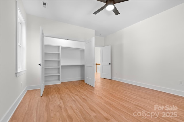 unfurnished bedroom featuring a ceiling fan, baseboards, visible vents, light wood finished floors, and a closet