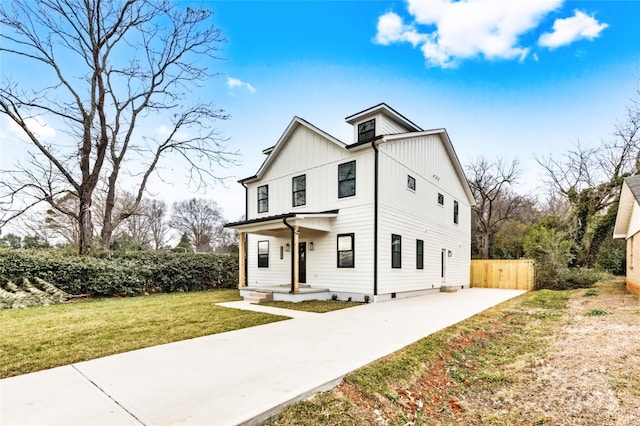 modern farmhouse style home featuring fence, a front lawn, and board and batten siding