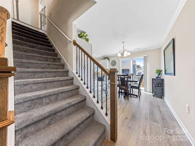 stairs featuring a chandelier, hardwood / wood-style floors, and crown molding