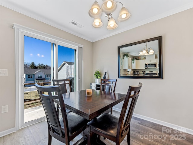 dining room featuring crown molding, wood-type flooring, and an inviting chandelier