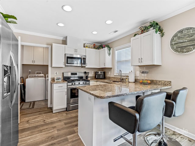 kitchen with kitchen peninsula, stainless steel appliances, white cabinetry, and sink