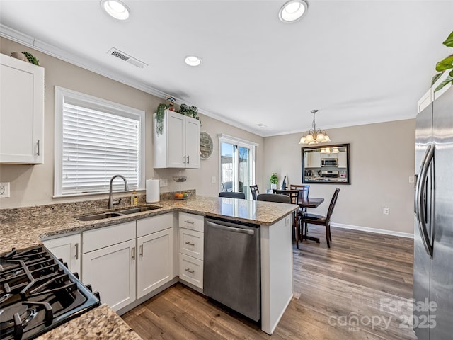 kitchen with crown molding, sink, appliances with stainless steel finishes, white cabinetry, and kitchen peninsula