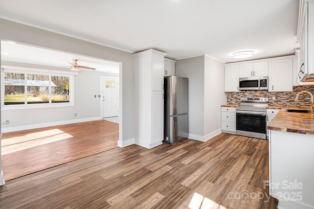 kitchen with sink, white cabinetry, appliances with stainless steel finishes, and wood counters