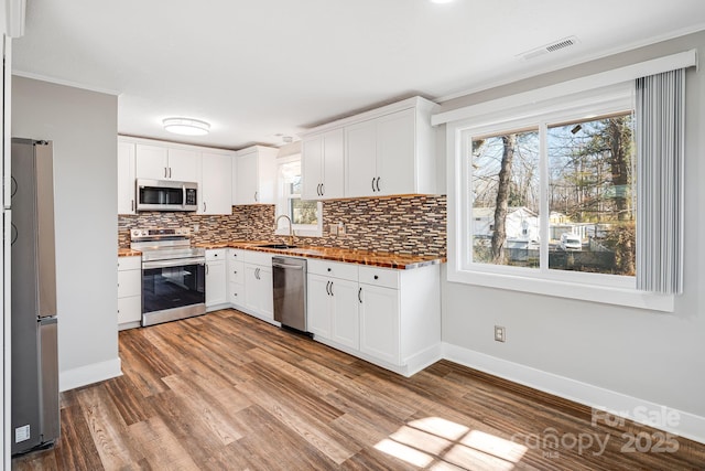 kitchen with stainless steel appliances, decorative backsplash, and white cabinetry