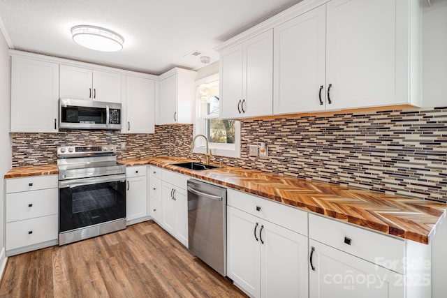 kitchen featuring wooden counters, sink, stainless steel appliances, and white cabinetry