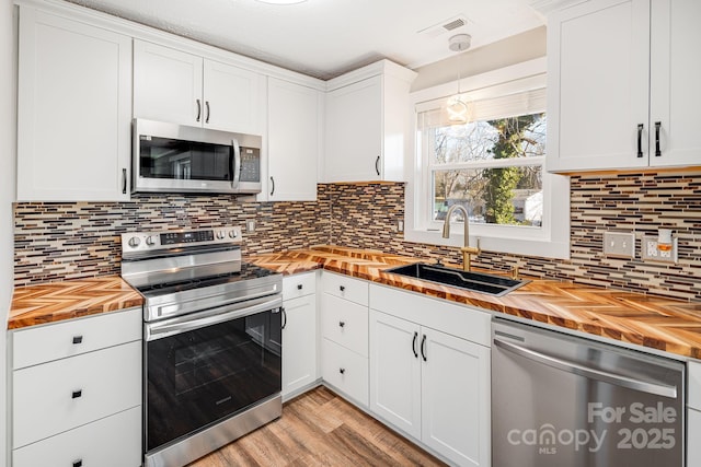 kitchen featuring sink, white cabinets, appliances with stainless steel finishes, and wood counters