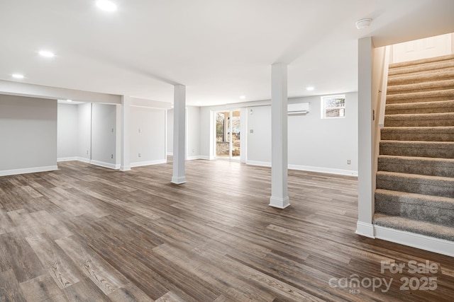 basement featuring an AC wall unit and wood-type flooring