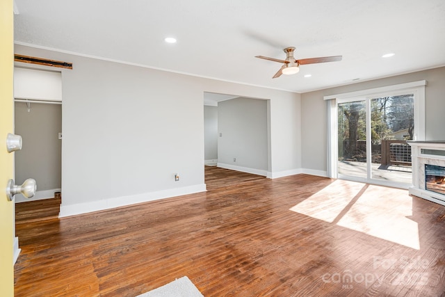 unfurnished living room with ceiling fan, dark hardwood / wood-style flooring, and crown molding