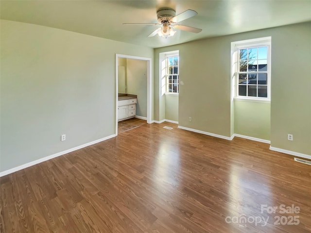 unfurnished bedroom featuring ensuite bath, ceiling fan, and hardwood / wood-style floors