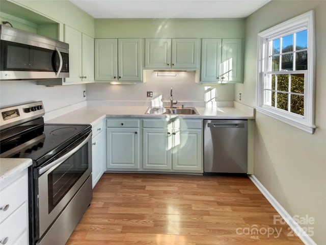 kitchen featuring white cabinets, stainless steel appliances, light hardwood / wood-style floors, and sink