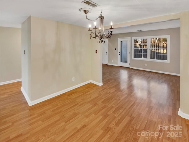 empty room with a chandelier and wood-type flooring