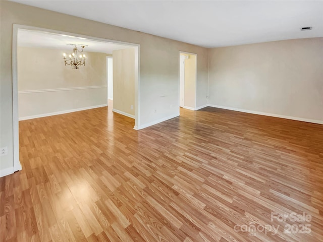 unfurnished room featuring light hardwood / wood-style floors and a notable chandelier