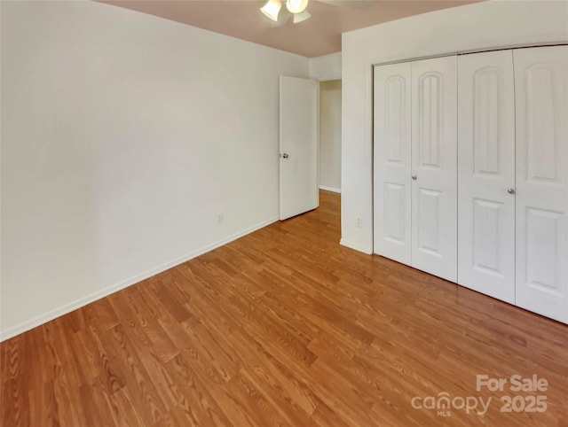 unfurnished bedroom with ceiling fan, a closet, and hardwood / wood-style flooring