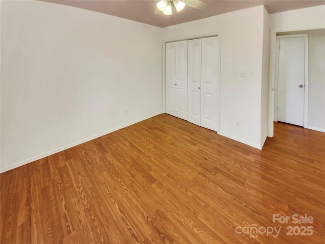 unfurnished bedroom with wood-type flooring, a closet, and ceiling fan