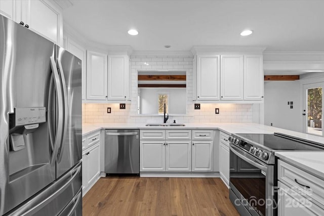 kitchen featuring white cabinetry, hardwood / wood-style flooring, sink, appliances with stainless steel finishes, and decorative backsplash