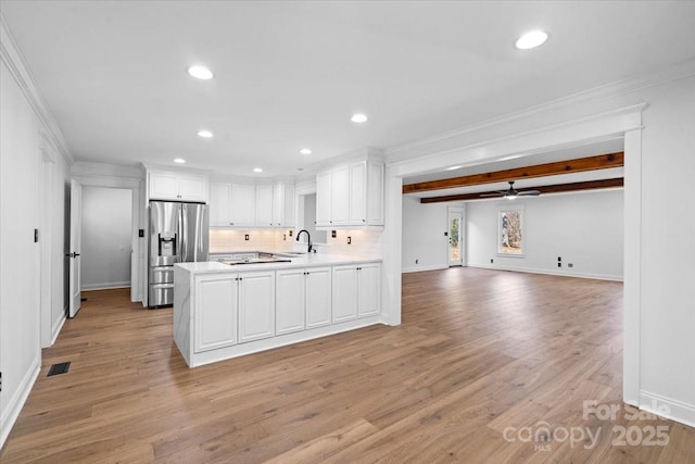 kitchen featuring white cabinetry, kitchen peninsula, stainless steel fridge with ice dispenser, sink, and crown molding