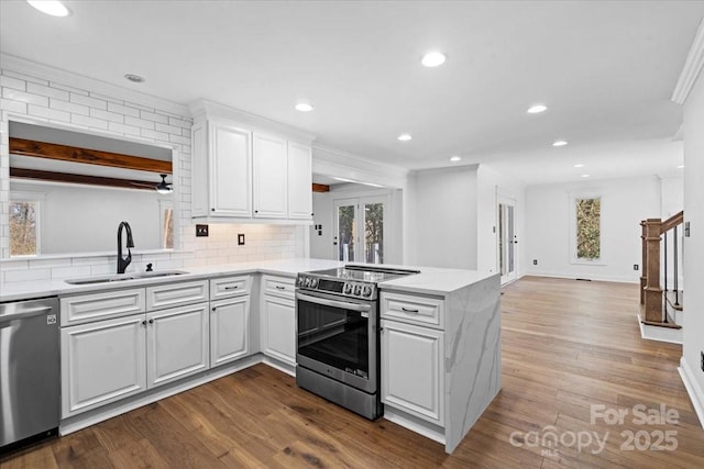 kitchen featuring sink, white cabinetry, stainless steel appliances, kitchen peninsula, and hardwood / wood-style flooring