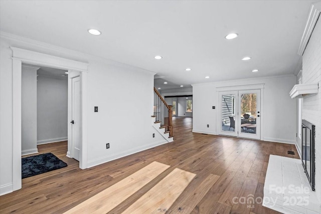 unfurnished living room featuring a brick fireplace, crown molding, and hardwood / wood-style floors