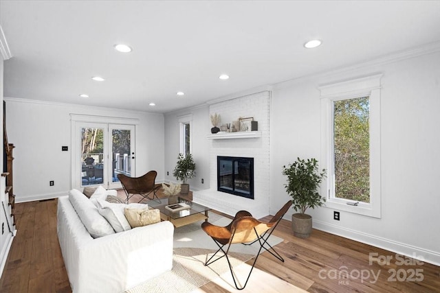 living room featuring ornamental molding, hardwood / wood-style floors, and a brick fireplace