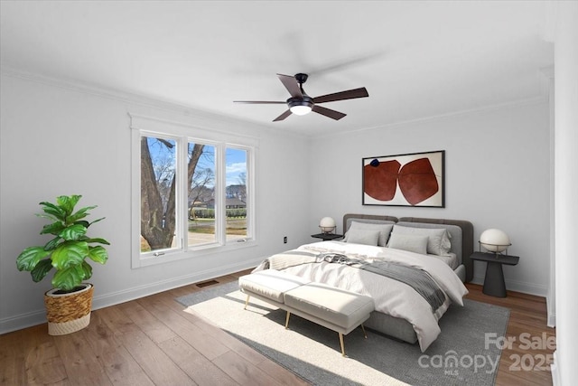 bedroom with crown molding, ceiling fan, and wood-type flooring