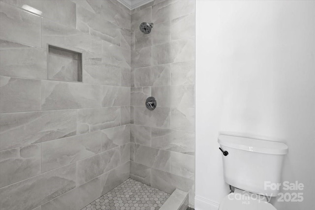 bathroom featuring tiled shower and toilet