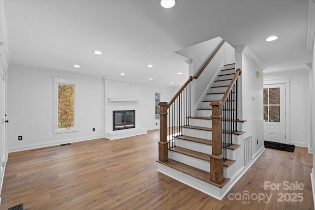 stairs with a brick fireplace and hardwood / wood-style floors