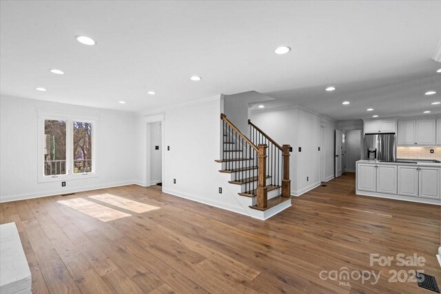 unfurnished living room with crown molding and wood-type flooring