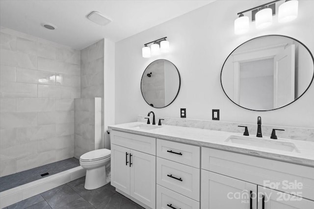 bathroom featuring tiled shower, vanity, and toilet