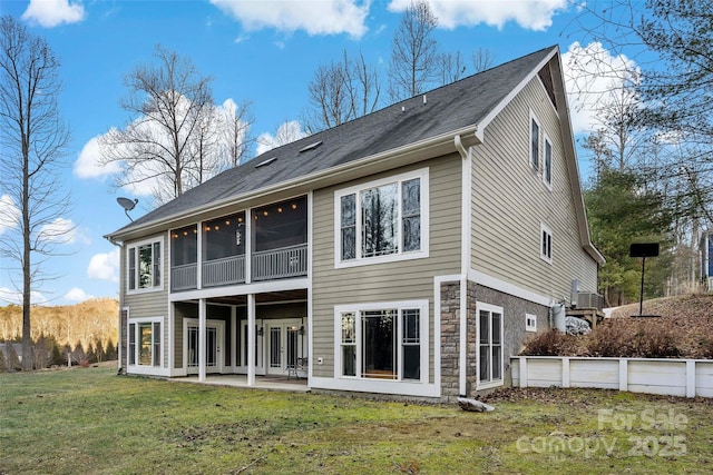 rear view of house with a patio area, stone siding, a sunroom, and a yard