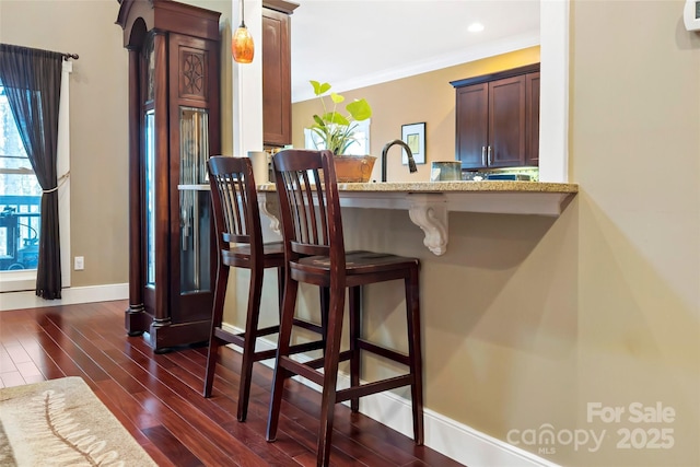 bar featuring dark wood-style flooring, pendant lighting, recessed lighting, ornamental molding, and baseboards