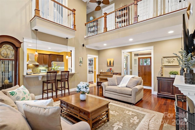 living area featuring crown molding, dark wood finished floors, baseboards, and ceiling fan