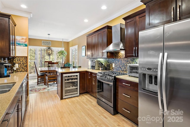 kitchen with wine cooler, hanging light fixtures, appliances with stainless steel finishes, wall chimney range hood, and a peninsula