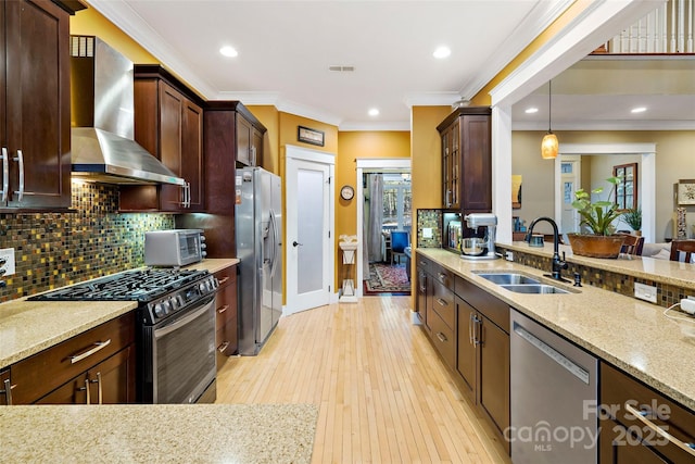 kitchen with pendant lighting, stainless steel appliances, visible vents, a sink, and wall chimney exhaust hood