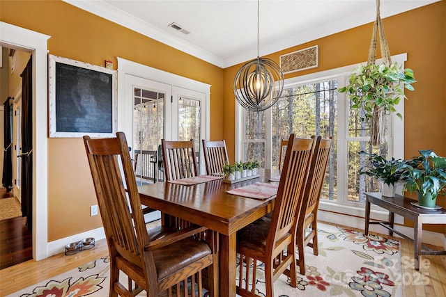 dining area with ornamental molding, light wood finished floors, plenty of natural light, and visible vents