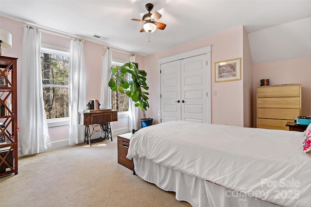 bedroom featuring light colored carpet, a ceiling fan, baseboards, visible vents, and a closet